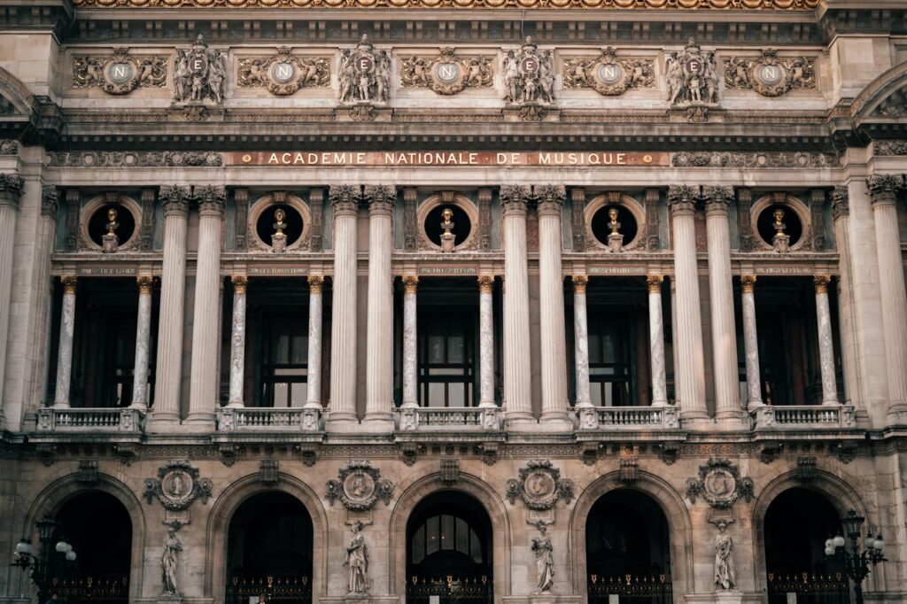 Detailed view of the Palais Garnier facade, highlighting its grand architecture and sculptures in Paris, France.