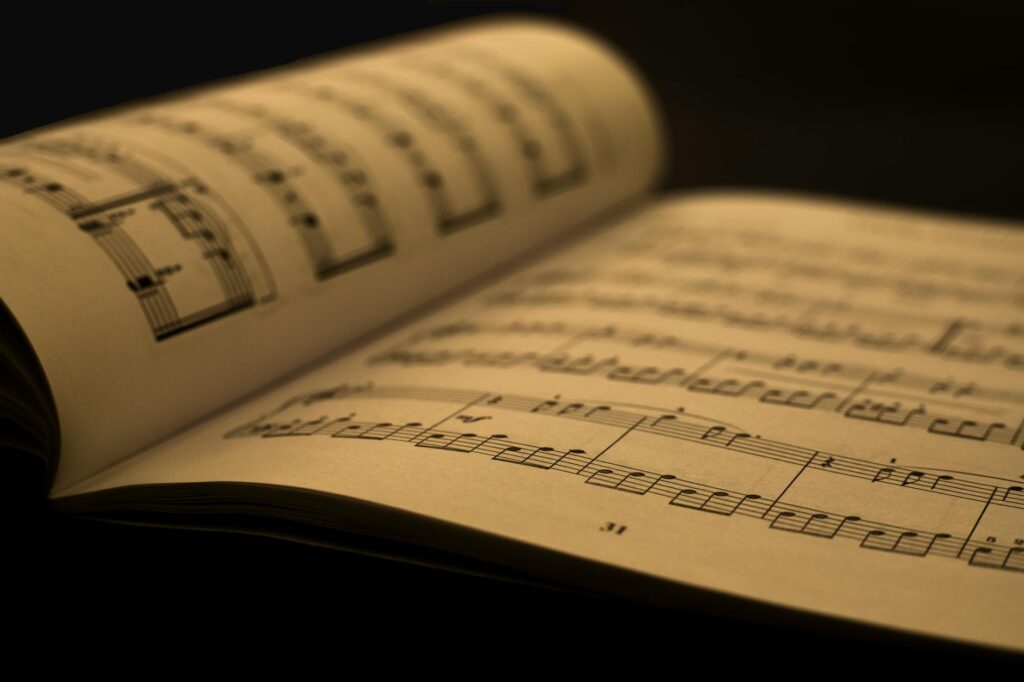Detailed close-up of an open music sheet book, showcasing musical notes and composition in warm tones.