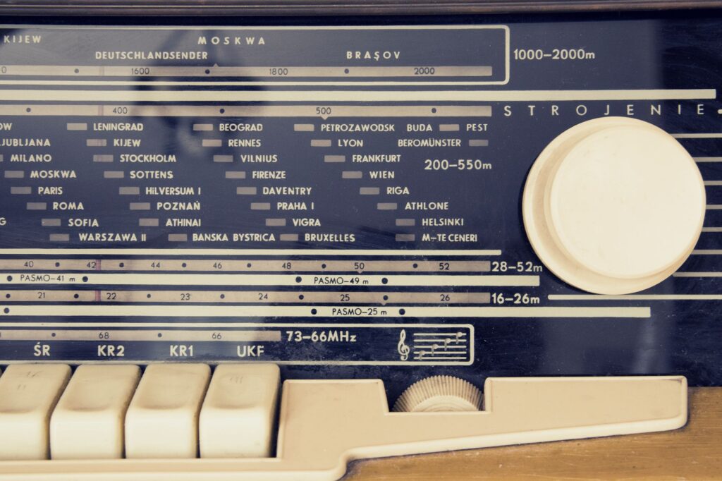 A detailed view of a vintage radio's tuning dial with city stations displayed.