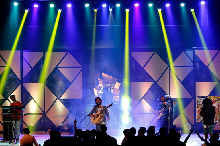 Groupe sur scène avec un jeu de lumières colorées, lors d'un concert en salle