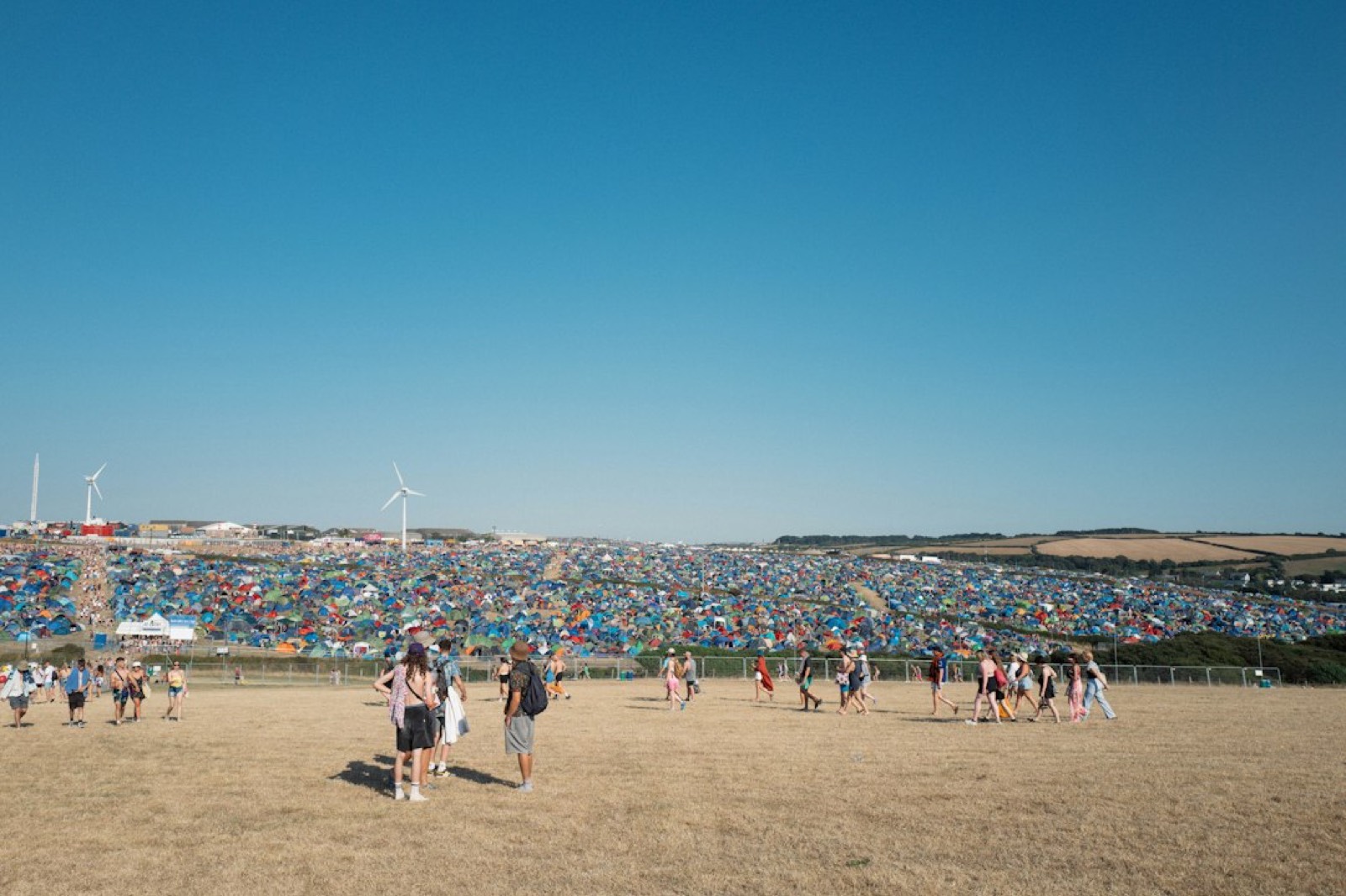 Vue aérienne d'un camping de festival, rangées de tentes serrées dans une prairie